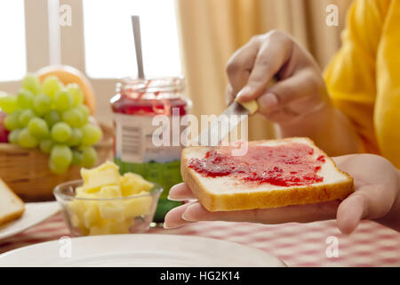 Donna marmellata di spandimento sul pane Foto Stock