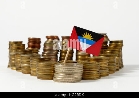 Antigua e Barbuda bandiera sventola con la pila di monete di denaro Foto Stock