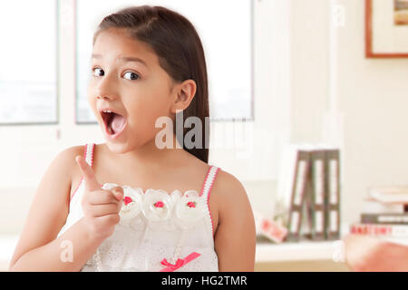 Ritratto di ragazza sorridente tirando facce buffe che mostra il dito indice Foto Stock