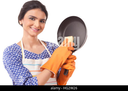 Giovane donna indiana holding arnese da cucina contro uno sfondo bianco Foto Stock