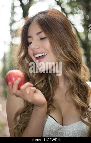 Sorridente giovane donna mangiare mela rossa Foto Stock