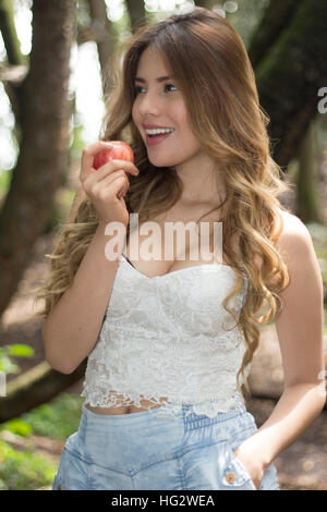 Sorridente giovane donna di mangiare un Apple Foto Stock