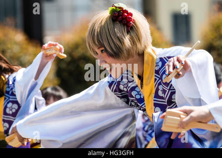 Yosakoi giapponese festival. Giovane studente universitario donna ballerino tinti con capelli biondi, sporgersi in avanti, sorridente. Vista laterale. Foto Stock