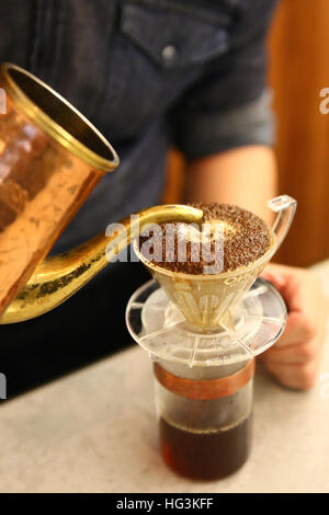 Barista versando acqua sul caffè macinato con filtro Foto Stock