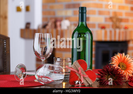 Natura morta con bottiglie di vino, bicchieri, fiori e simbolo del cuore, sullo sfondo di un caminetto in mattoni Foto Stock