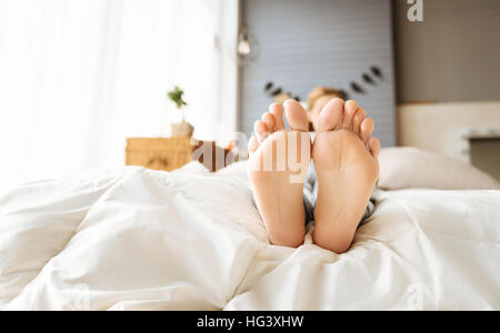 Close up di gravidanza womans piedi giacente a letto Foto Stock