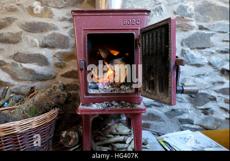 Vecchio Jotul 602C woodburning stufa con porta aperta logs fuoco ardente fiamme in un cottage in pietra in Wales UK KATHY DEWITT Foto Stock