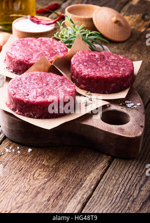 Materie organiche di macinato di manzo, polpette rotonde per realizzare in casa burger sul tagliere di legno Foto Stock