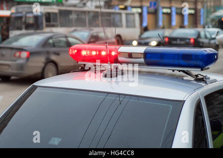 Luce blu lampeggiante sulla vista closeup top della polizia auto, sfocatura  paesaggio urbano sfondo. La barra luminosa e sirena montata sul tetto,  veicolo di emergenza, polizia comunale Foto stock - Alamy