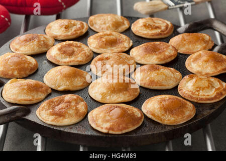 Cottura in forno olandese mini pancake chiamato poffertjes in una padella speciale pan Foto Stock