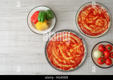 Pronta la pasta per pizza in forme per la cottura e l'ingrediente in orizzontale Foto Stock