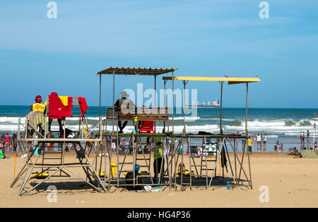 Bagnini sulla piattaforma di osservazione vegli su di molte persone sconosciute sulla spiaggia contro l oceano e dello skyline di blu Foto Stock