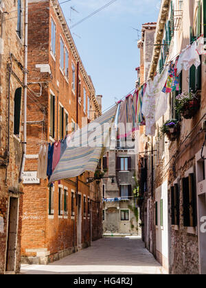 Tipico scenario di strada a Venezia, con lavaggi appesi tra le case cittadine. Foto Stock