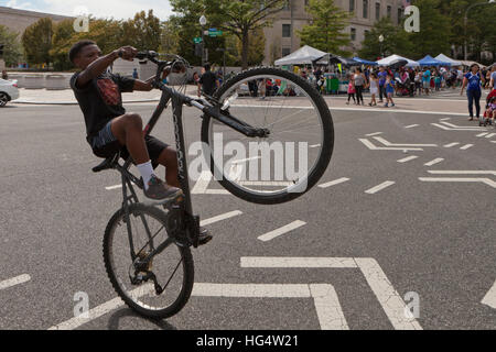 Ragazzo afro-americano di eseguire un wheelie in bicicletta - Washington DC, Stati Uniti d'America Foto Stock