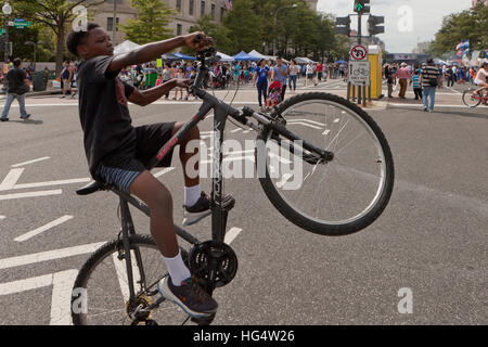 Ragazzo afro-americano di eseguire un wheelie in bicicletta - Washington DC, Stati Uniti d'America Foto Stock