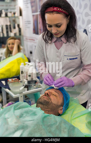 Cosmetologia non riconosciuta terapista dimostra il ringiovanimento trattamenti su un medioevo uomo al XVI Congresso Nazionale di bellezza. Foto Stock