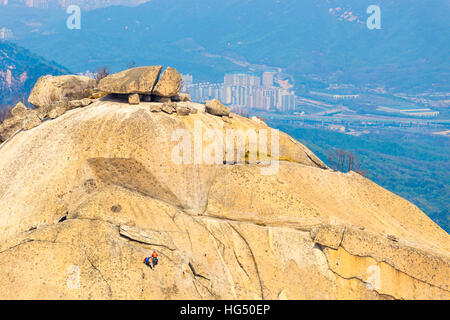 Gli alpinisti Insubong arrampicata su roccia, la seconda vetta più alta in corrispondenza Bukhansan montagna con vista della città sottostante in Seoul Sud Foto Stock