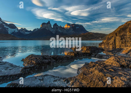 Ampio angolo di visione del Cuernos del Paine e Monte Almirante Nieto con rocce e il Lago Pehoe in primo piano. Nuvole lenticolari stanno cominciando a f Foto Stock