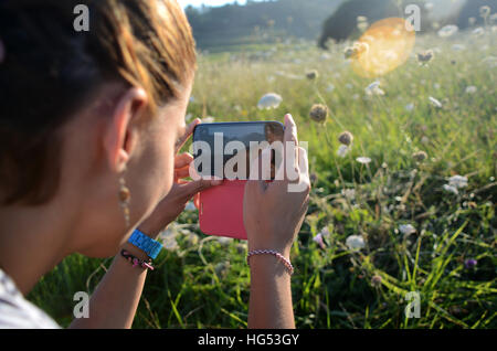 Giovane donna prende le foto della natura con il suo telefono cellulare Foto Stock