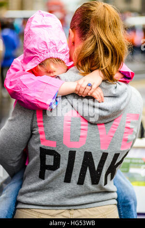 Donna in 'amore rosa' hoodie porta bambino indossando cagoule rosa a Edimburgo in Scozia Foto Stock