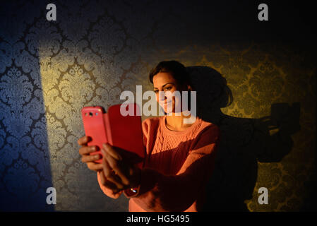 Giovane donna prende un selfie con telefono mobile nella camera di albergo Kemi, Lapponia Foto Stock