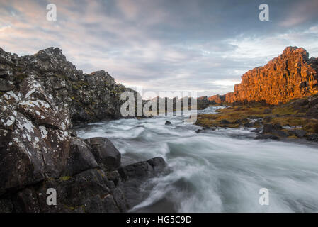 Un fiume scorre dalla cascata Oxarafoss presso sunrise a Thingvellir National Park, UNESCO, Islanda, regioni polari Foto Stock