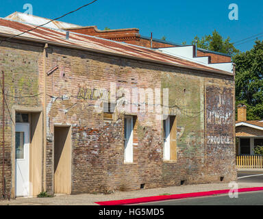 Il vecchio edificio in mattoni con tetto dello stagno con il vecchio sbiadito annunci pubblicitari sul lato Foto Stock