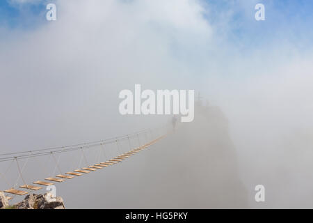 L'uomo oltre il divario sul ponte sospeso nella nebbia Foto Stock