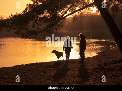 Giovane a piedi il loro cane accanto a un lago. Foto Stock