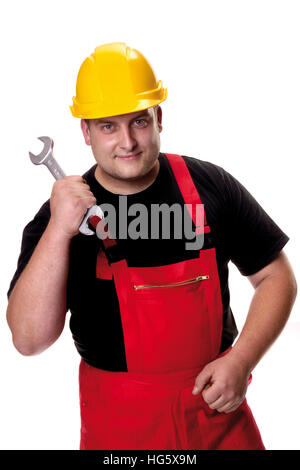 Tradesman indossando giallo hardhat tenendo una chiave aperta Foto Stock
