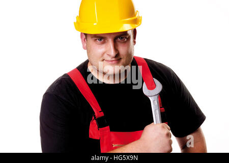 Tradesman indossando giallo hardhat tenendo una chiave aperta Foto Stock