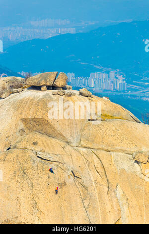 Gli alpinisti climbing Insubong picco Bukhansan in montagna con vista della vallata sottostante a Seul, Corea del Sud Foto Stock