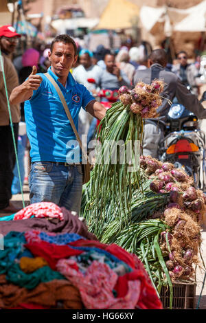 Elkhorbat, Marocco. Giovane berbero uomo cipolle di vendita nel mercato. Foto Stock