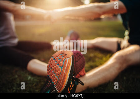 Piedi del giovane uomo e donna che esercitano insieme nel parco. Focus sulle scarpe del giovane lavorando insieme. Foto Stock