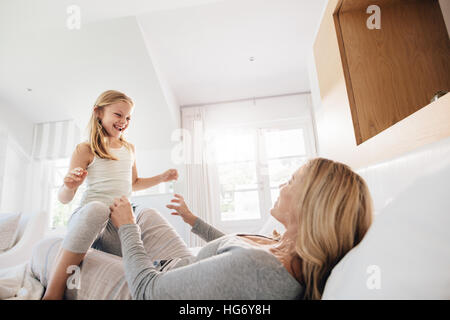 Piscina shot della bambina gioca con sua madre sul letto. Madre e figlia giocando in camera da letto. Foto Stock