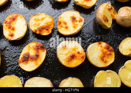 Arrosto di fette di patate su un nero piastra di cottura Foto Stock