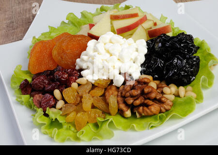 Vitamina insalata con dadi, mele, frutta secca e formaggio in foglie di lattuga Foto Stock