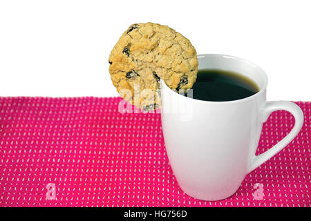 Farina di avena cookie con uvetta sul bordo della tazza bianca con caffè nero Foto Stock