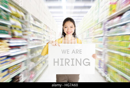 Giovane donna asiatica mano azienda "siamo affitto' segno bordo nel mercato o department store. Foto Stock