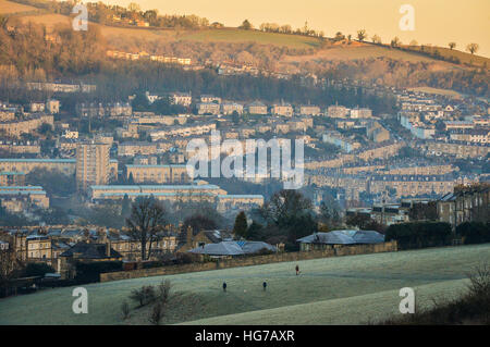 Dog walkers in un gelido campo come il sole sorge sopra la città di Bath in un freddo, clear mattina nel sud ovest dell'Inghilterra. Foto Stock