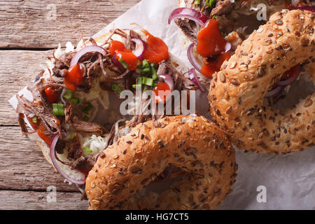 Bagel con tirato il maiale, le cipolle cavolo e salsa di close-up sul tavolo. vista orizzontale dal di sopra Foto Stock