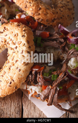 Bagel con verdure e carne di maiale tirato vicino sul piano verticale. Foto Stock