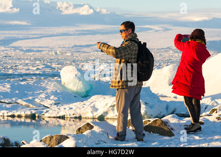 Due turisti scattare foto di paesaggi spettacolari a Jokulsarlon laguna glaciale, sul bordo del Vatnajokull National Park, Islanda nel gennaio Foto Stock