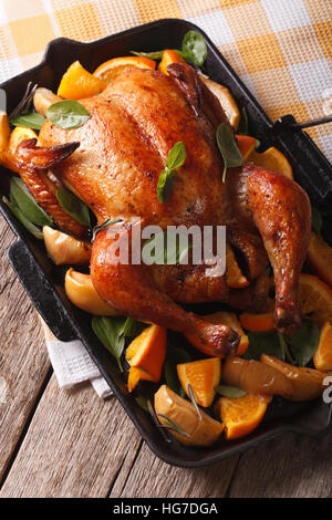 Delizioso pollo arrosto con arance e mele in un tegame verticale. Foto Stock