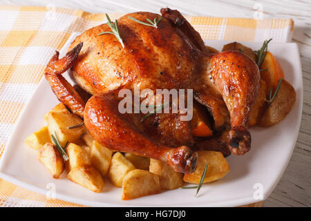 Tutto il pollo arrosto con le arance e patate close-up su una piastra orizzontale. Foto Stock