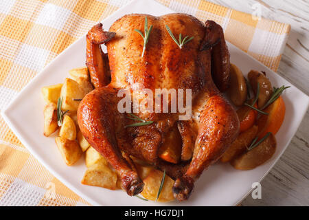 Tutto il pollo arrosto con le arance, patate e mele close-up su una piastra orizzontale. Foto Stock