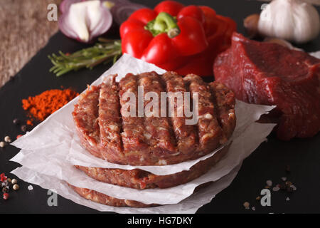 La cottura di hamburger cotolette di close-up e gli ingredienti sulla scheda. Posizione orizzontale Foto Stock