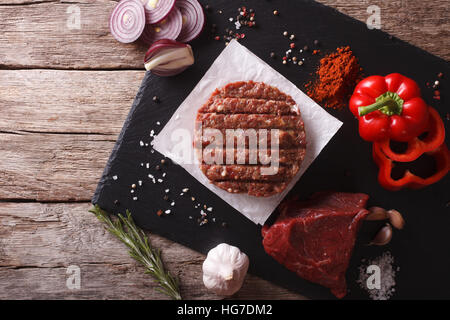 Materie burgers cotolette con gli ingredienti sul tavolo. vista orizzontale dal di sopra Foto Stock