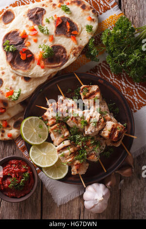 Pollo Tikka su spiedini, naan pane piatto e chutney closeup. verticale vista superiore Foto Stock