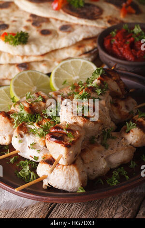 Indian pollo tikka kebab spiedini su close-up su una piastra e naan verticale. Foto Stock